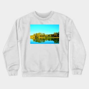 Scene from Lago Cedri in Lapedona with trees bathed in sunlight and the calm waters of the lake reflecting that lushness Crewneck Sweatshirt